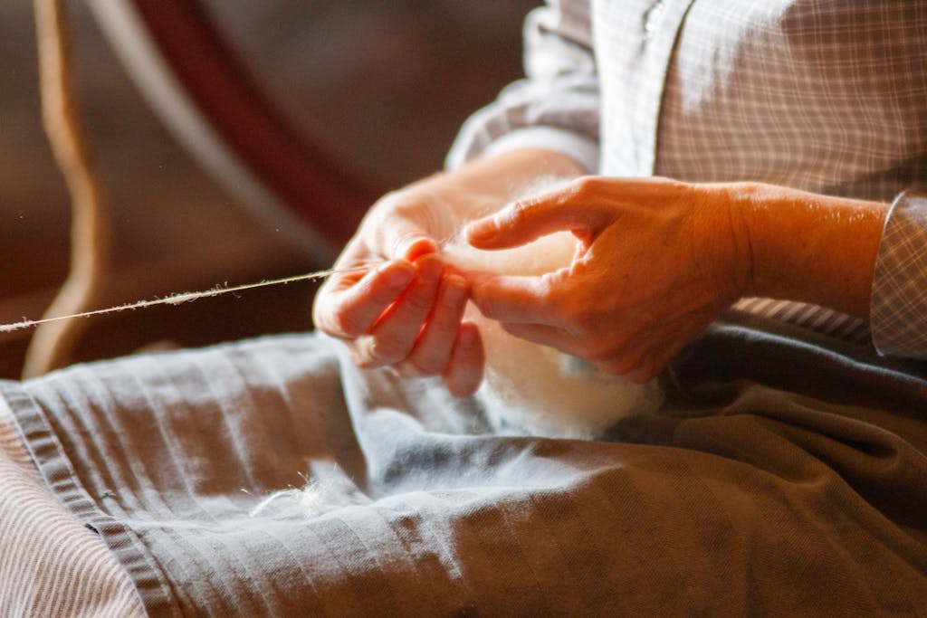 A person's hands skillfully spinning wool into yarn using traditional methods.